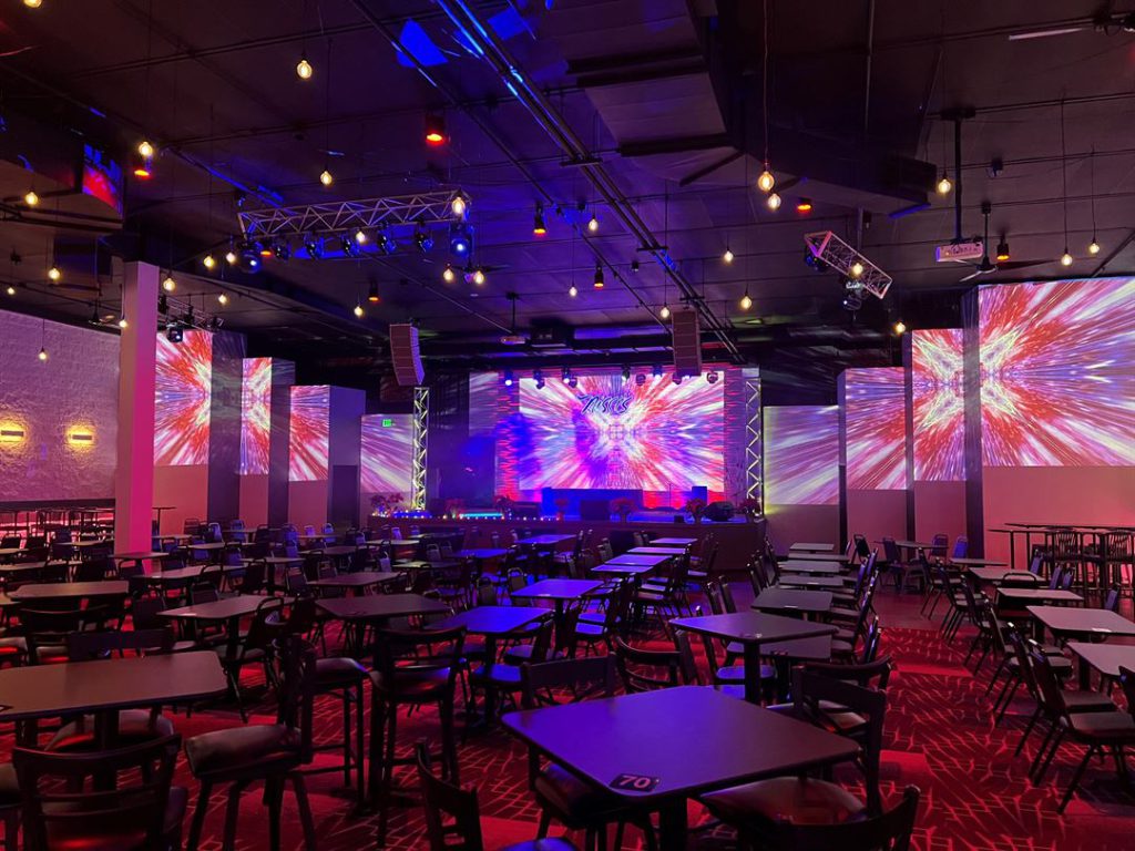 Tables and chairs facing Nissi’s stage and projection screens