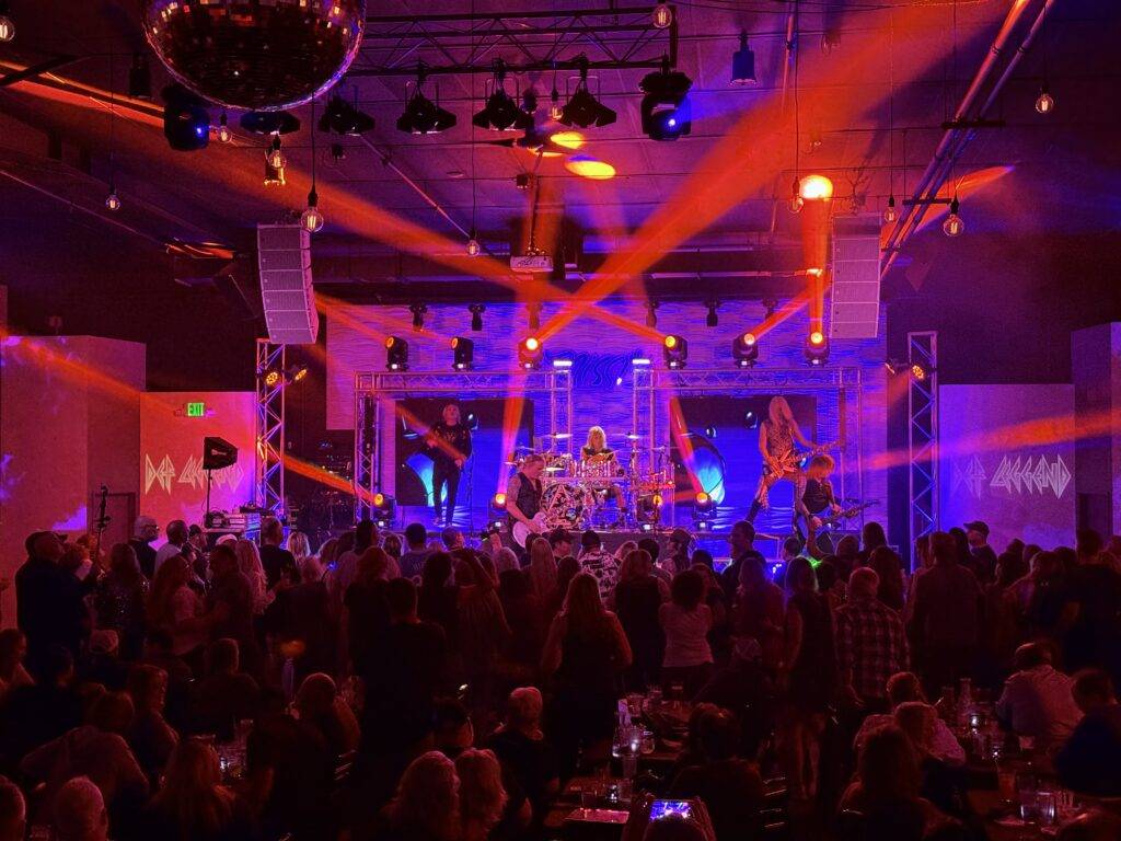 Crowd facing the stage under orange and purple concert lights