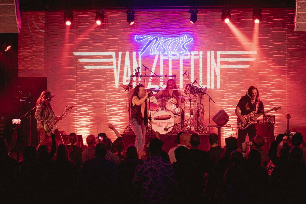 Live band and audience under red stage lighting