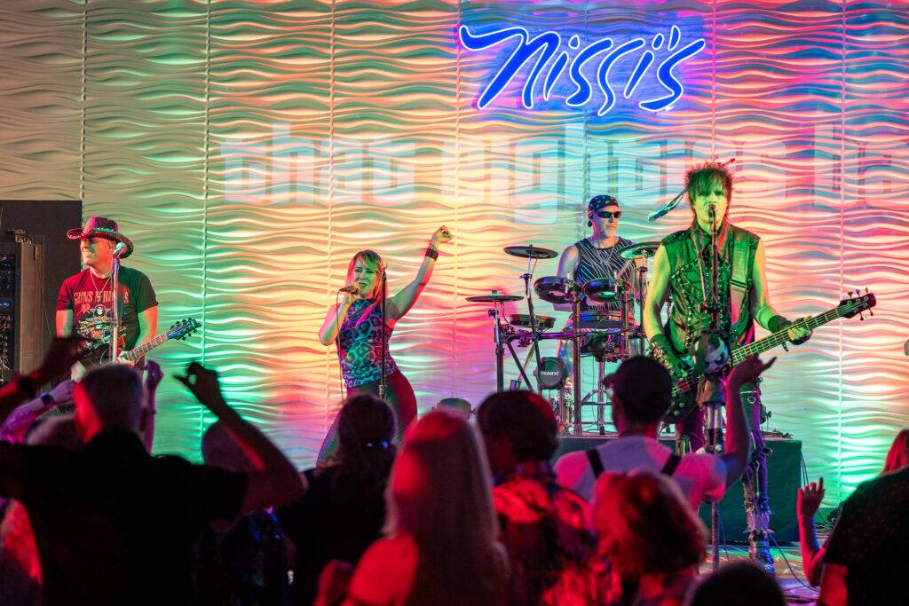 Band performing on the illuminated stage at Nissi’s