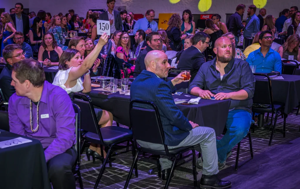 Guests raising bidding paddles during a gala at Nissi’s