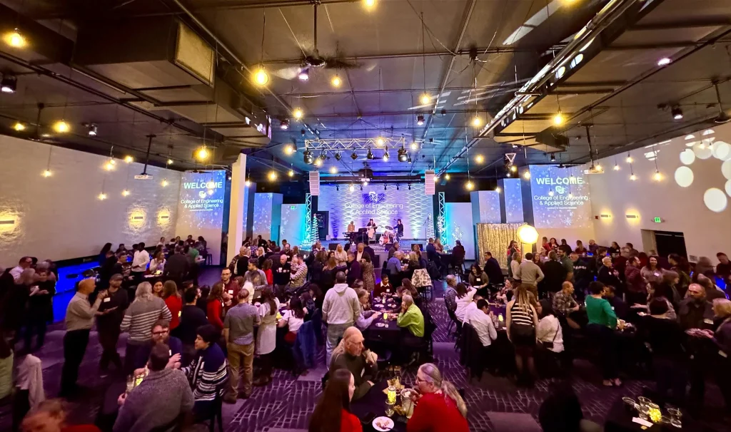 Holiday party guests gathered around tables beneath warm lights at Nissi’s