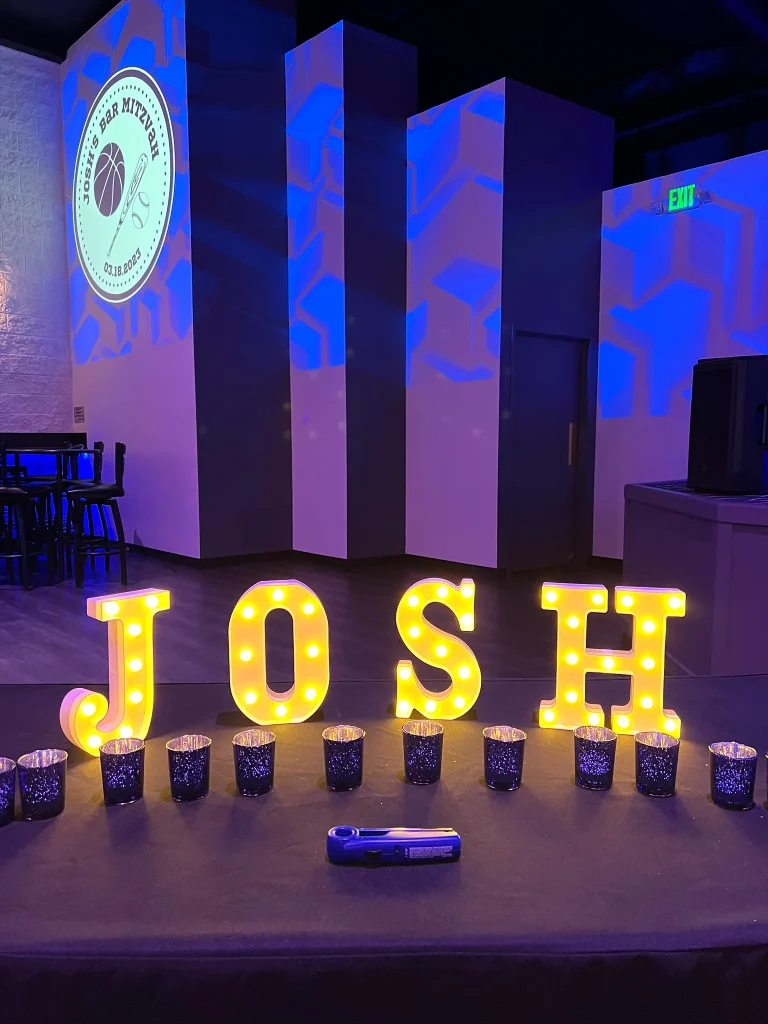 Personalized mitzvah stage with illuminated letters and projections at Nissi’s