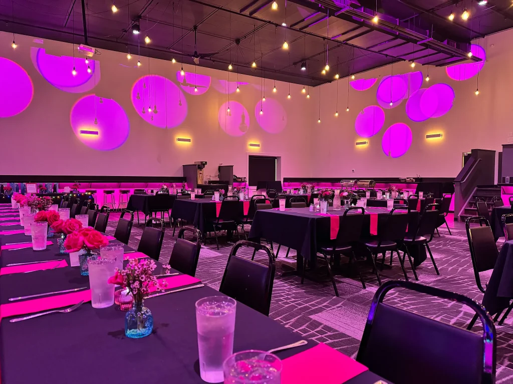 Mitzvah tables and hanging decorations beneath pink lighting at Nissi’s