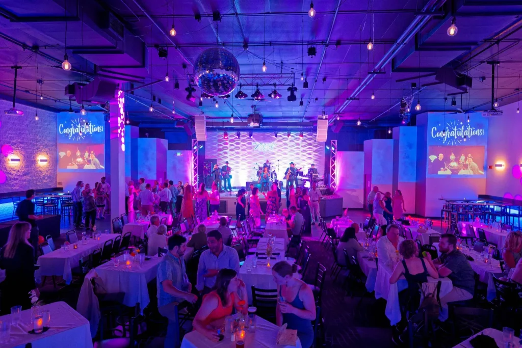 Wedding reception guests dancing and dining beneath colorful lights at Nissi’s
